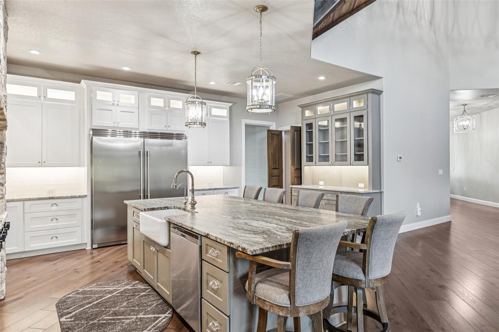 12877 Foutch Road Pilot Point, TX 76258 - Photo 13 of 40 a kitchen with stainless steel appliances kitchen island granite countertop a table chairs and wooden floor