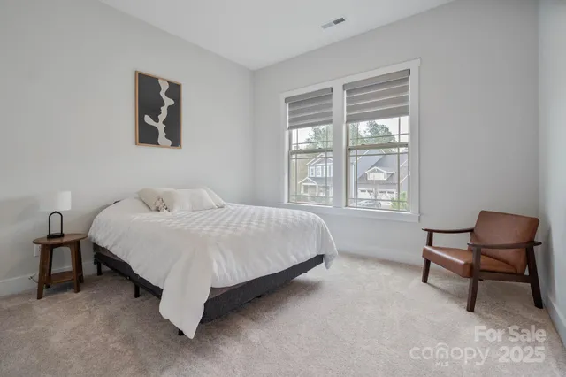 a bedroom with a bed chair and painting on the wall