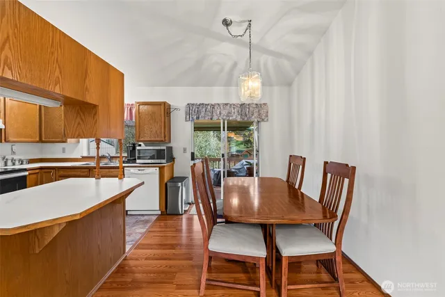 a kitchen with stainless steel appliances granite countertop a stove a refrigerator a dining table and chairs with wooden floor