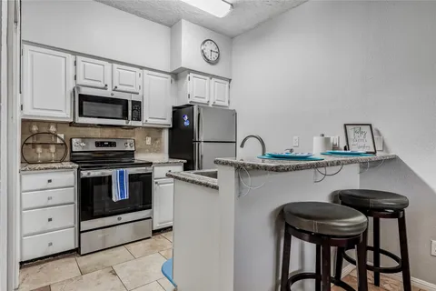 a kitchen with stainless steel appliances kitchen island a table chairs microwave and sink