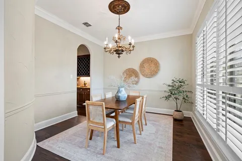 a dining room with chandelier and wooden floor