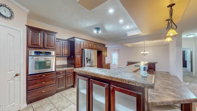 a kitchen with kitchen island granite countertop wooden cabinets and a refrigerator