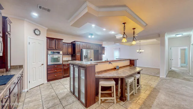 a kitchen with stainless steel appliances kitchen island granite countertop a table chairs sink and cabinets