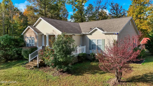 a view of a house with a yard and large trees