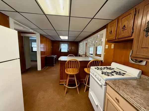 a kitchen with stainless steel appliances granite countertop a stove a refrigerator a sink dishwasher a dining table and chairs with wooden floor