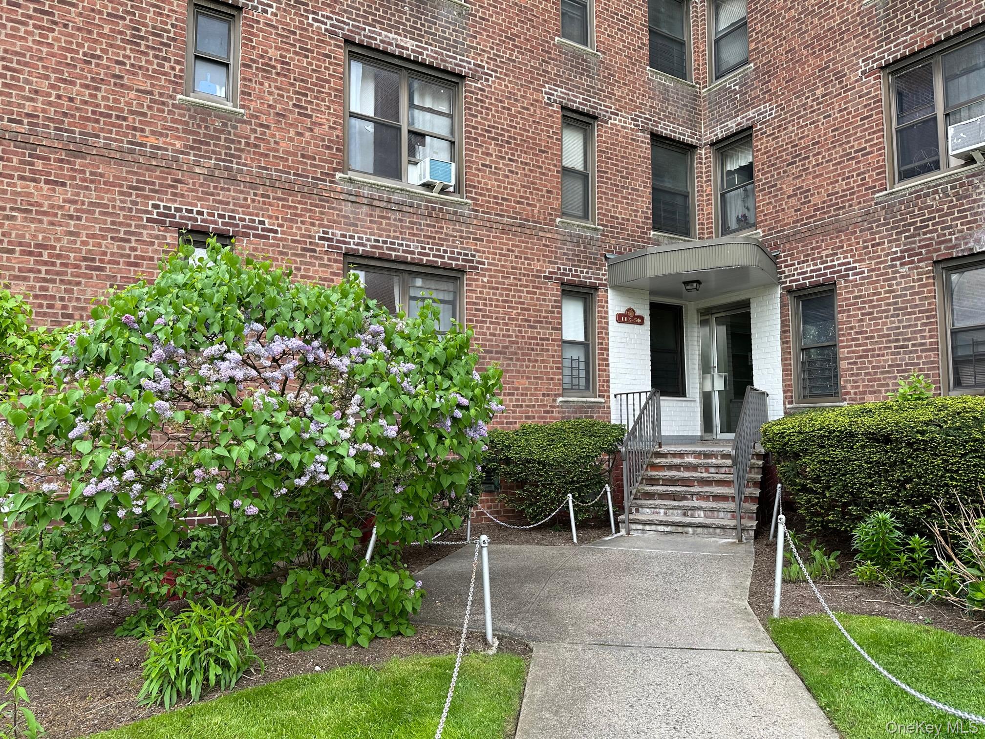 a view of a brick house with a yard and plants