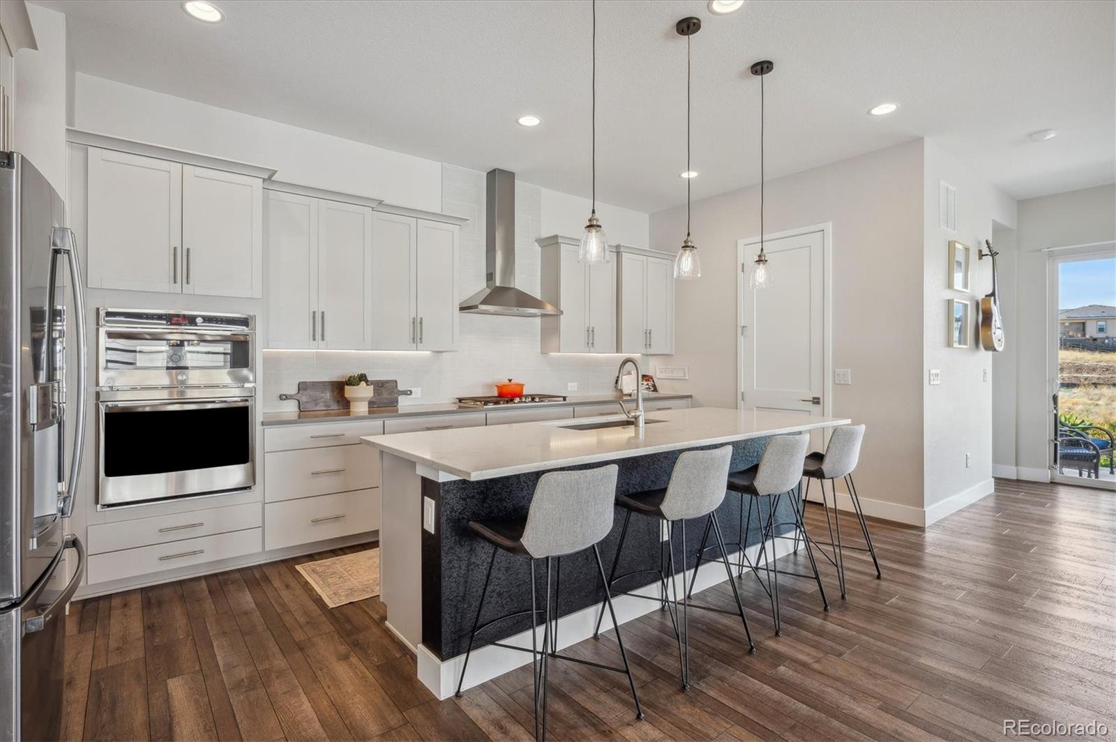 a kitchen with stainless steel appliances kitchen island granite countertop a table chairs sink and cabinets