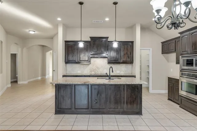 a kitchen with stainless steel appliances granite countertop a sink a stove a refrigerator a microwave oven with white cabinets