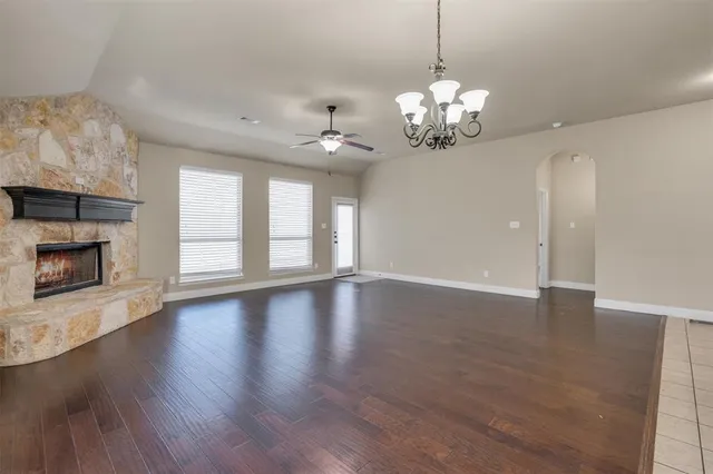 a view of an empty room with wooden floor and a fireplace