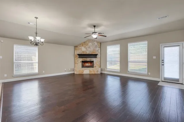 a view of an empty room with wooden floor fireplace and a window
