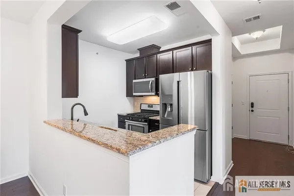 a kitchen with granite countertop a refrigerator and a sink
