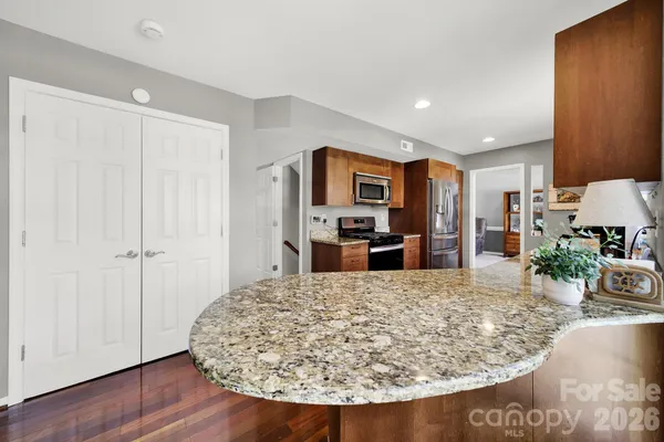 a kitchen with stainless steel appliances granite countertop a stove top oven a sink dishwasher and a microwave oven on the wooden floor