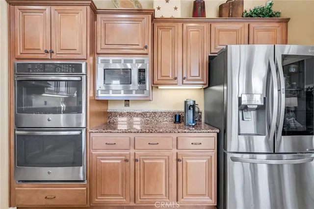 a kitchen with stainless steel appliances granite countertop a refrigerator and a stove top oven