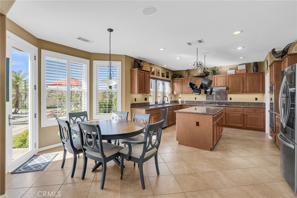 14143 Ashton Lane Riverside, CA 92508 - Photo 10 of 40 a kitchen with stainless steel appliances granite countertop a table chairs refrigerator and sink