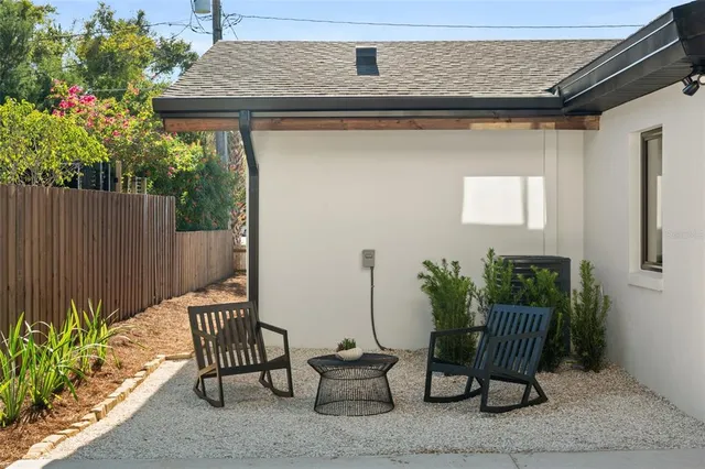 a view of a white house with a small yard and wooden fence