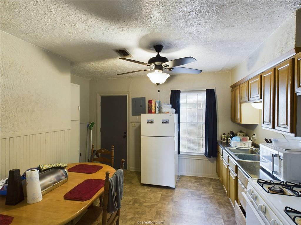 1316 Antone Street, Unit B Bryan, TX 77803 - Photo 3 of 7 Kitchen featuring white appliances, a textured ceiling, a wainscoted wall, a ceiling fan, and electric panel