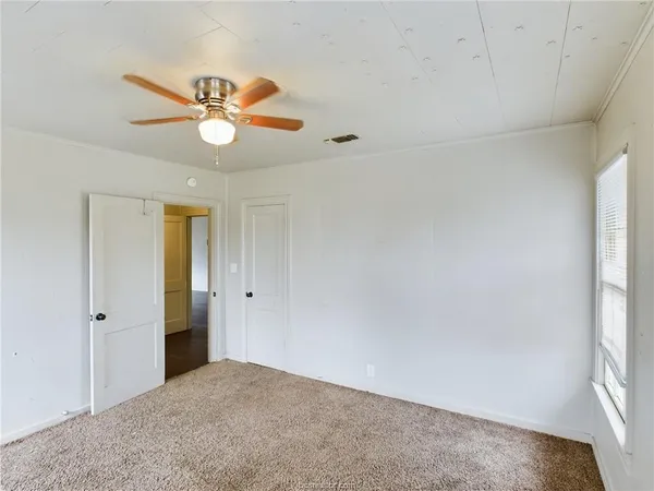 an empty room with windows and fan