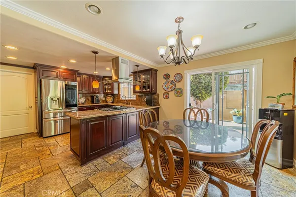 a kitchen with stainless steel appliances granite countertop a stove a refrigerator a kitchen island a dining table and chairs with wooden floor
