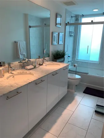 a spacious bathroom with a granite countertop sink a toilet mirror and bathtub