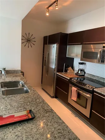 a kitchen with stainless steel appliances granite countertop a stove a sink and a refrigerator