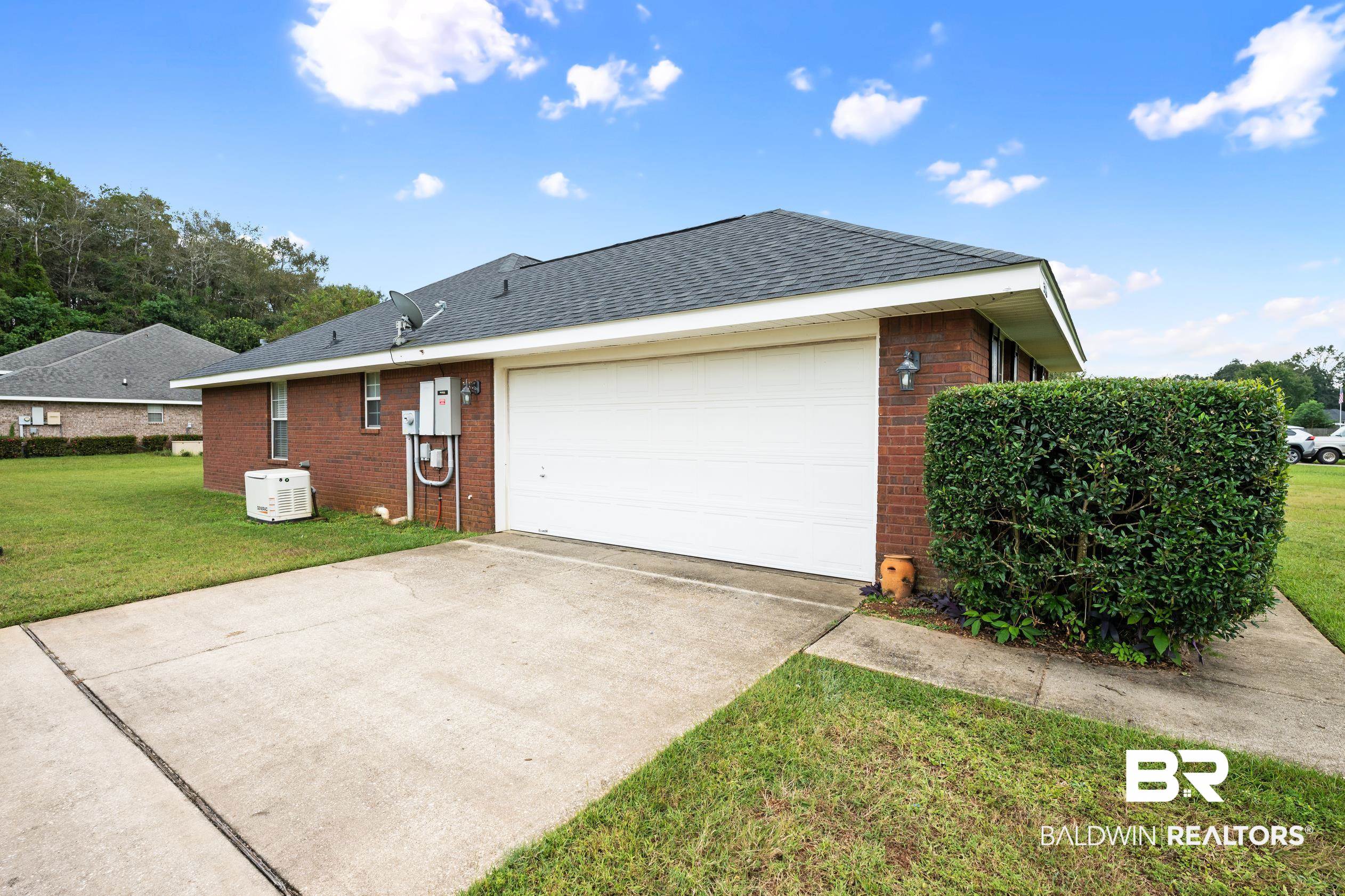 306 Monteith Oaks Drive Foley, AL 36535 - Photo 33 of 38 View of property exterior featuring brick siding, a lawn, driveway, a shingled roof, and a garage
