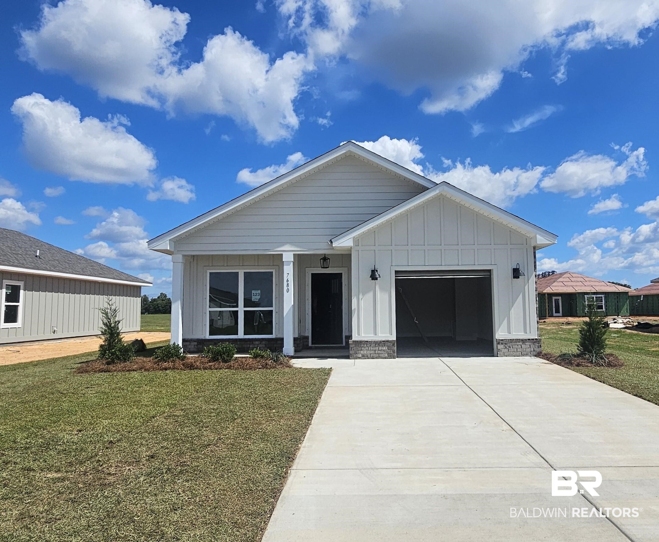 7680 Courant Circle Foley, AL 36535 - Photo 1 of 33 View of front of house featuring board and batten siding, a front yard, a garage, and driveway