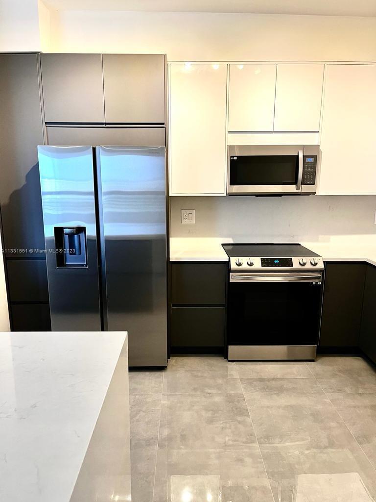 3530 Mystic Pointe Drive, Unit PH08 Aventura, FL 33180 - Photo 2 of 11 a kitchen with stainless steel appliances kitchen island granite countertop a refrigerator stove and microwave