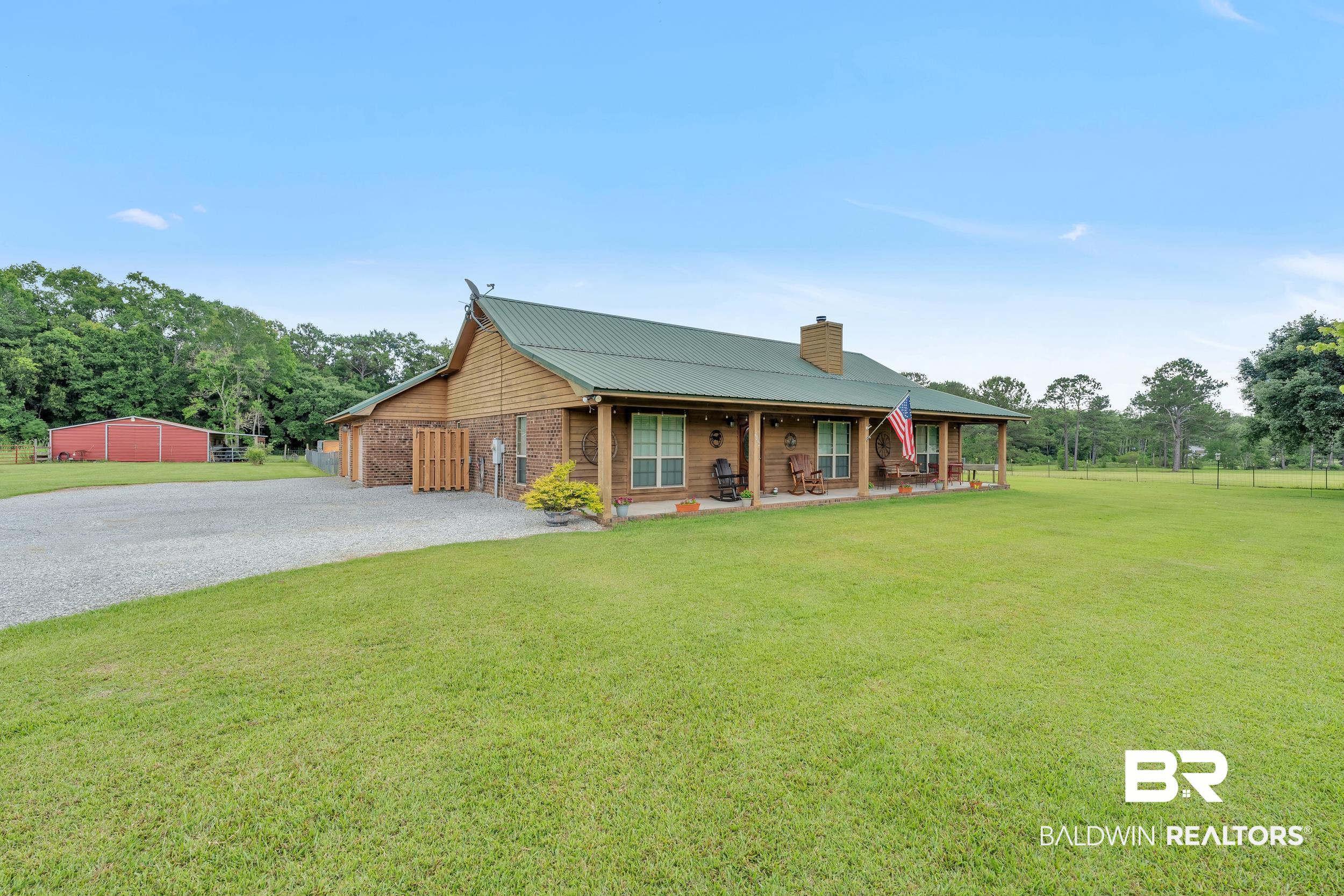 4062 River Road Theodore, AL 36582 - Photo 4 of 32 View of front of property with gravel driveway, a chimney, metal roof, and a porch