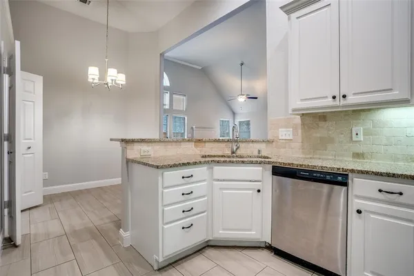 a kitchen with granite countertop white cabinets and a sink