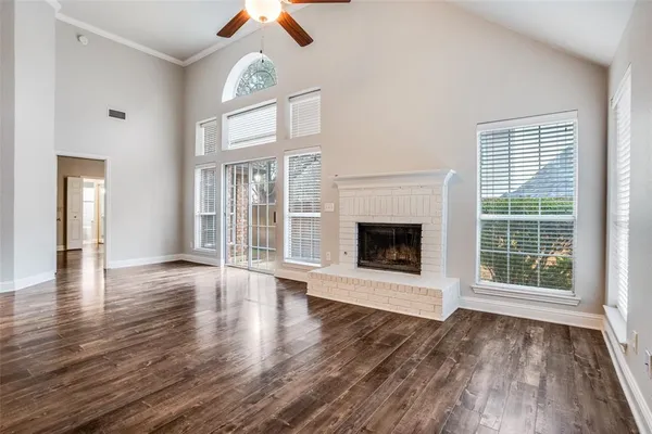 an empty room with wooden floor a fireplace and windows