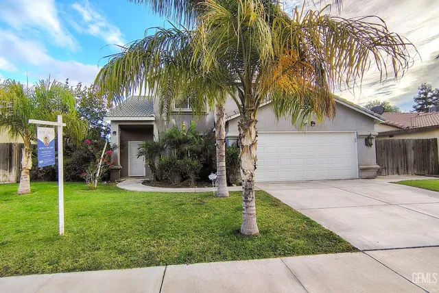 a front view of a house with a yard and palm trees