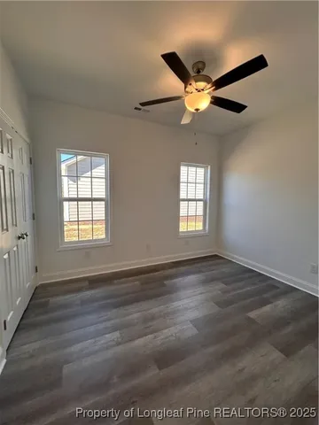 an empty room with wooden floor fan and windows