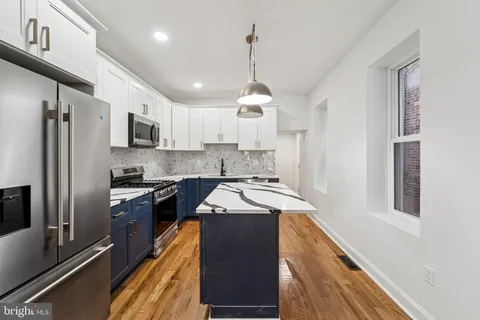 a kitchen with stainless steel appliances granite countertop a refrigerator a sink dishwasher a stove and white cabinets with wooden floor