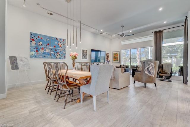 a dining room with wooden floor and large windows