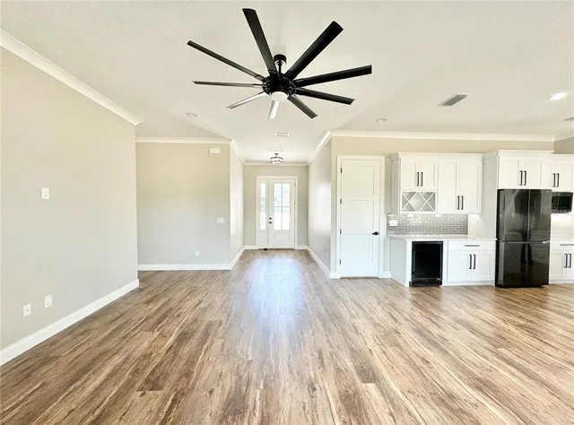 a view of a livingroom with a fireplace a ceiling fan and wooden floor