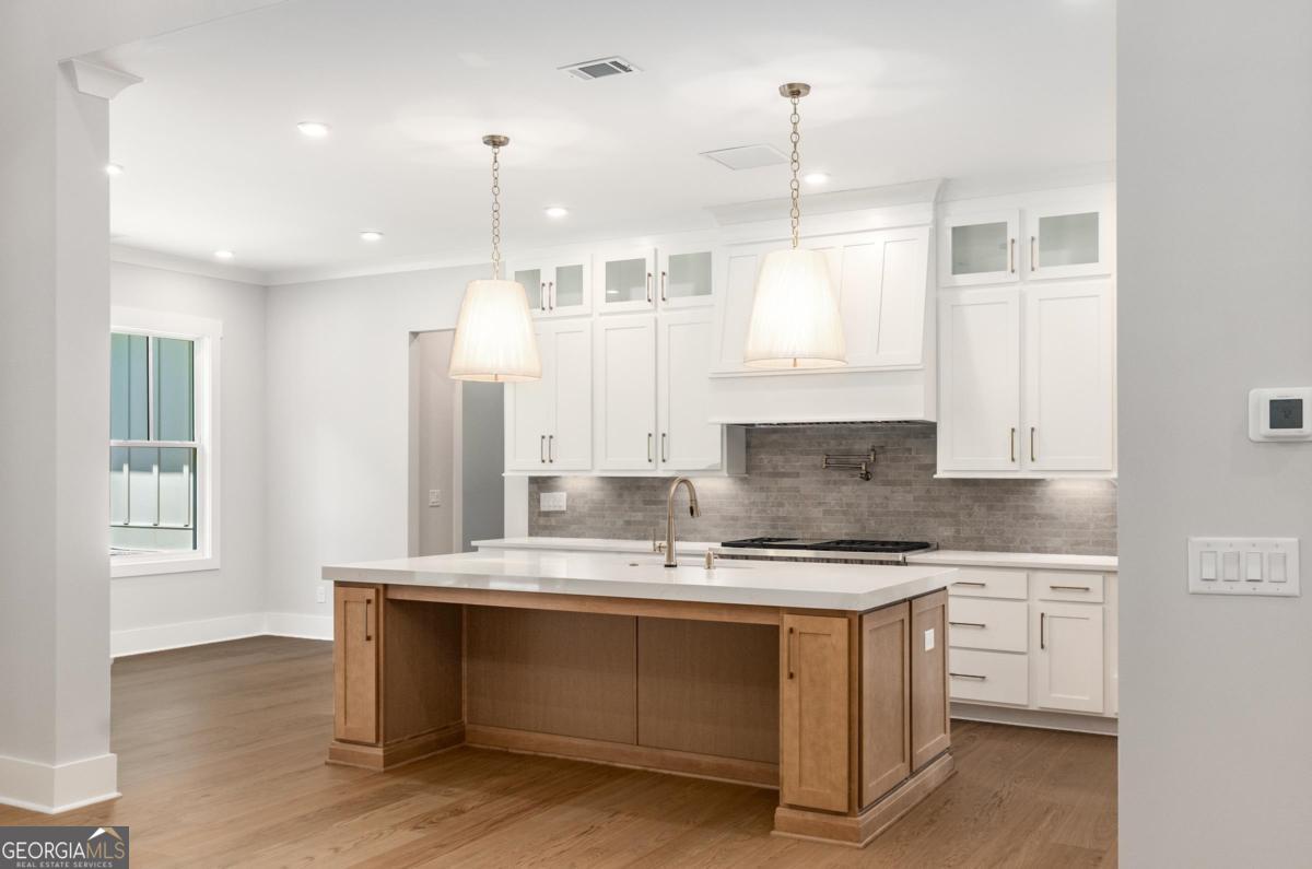 229 Eagles Way Eatonton, GA 31024 - Photo 14 of 61 a kitchen with kitchen island granite countertop a stove a sink and white cabinets with wooden floor