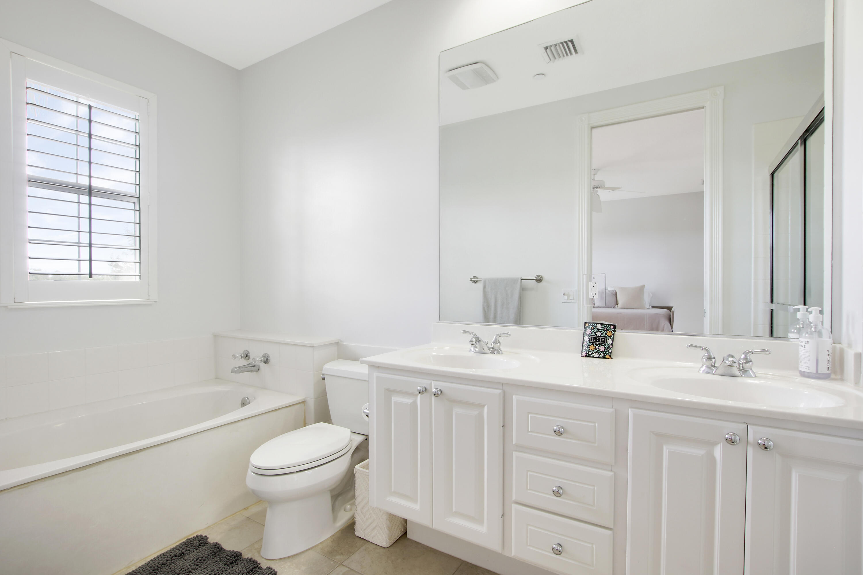3424 West Community Drive Jupiter, FL 33458 - Photo 19 of 25 a bathroom with a toilet a sink a tub and a mirror
