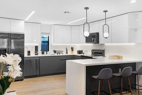 a kitchen with stainless steel appliances granite countertop a stove top oven a sink dishwasher and a dining table with wooden floor
