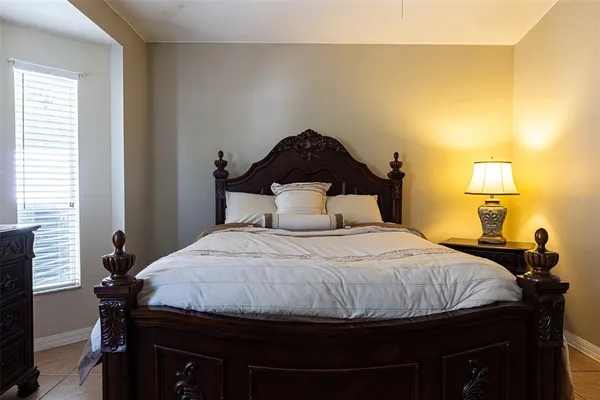 a bedroom with a bed and a lamp on dresser