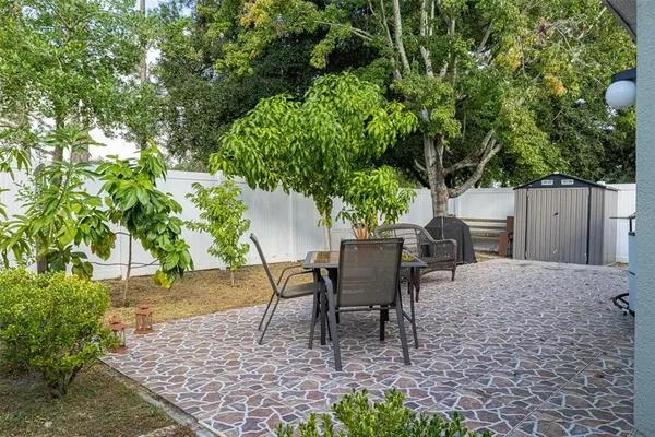a view of a backyard with table and chairs potted plants and large tree