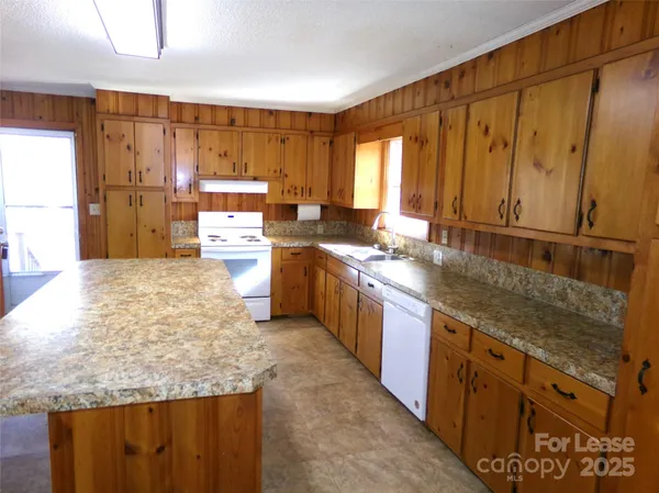a large kitchen with kitchen island granite countertop wooden cabinets a sink and a stove