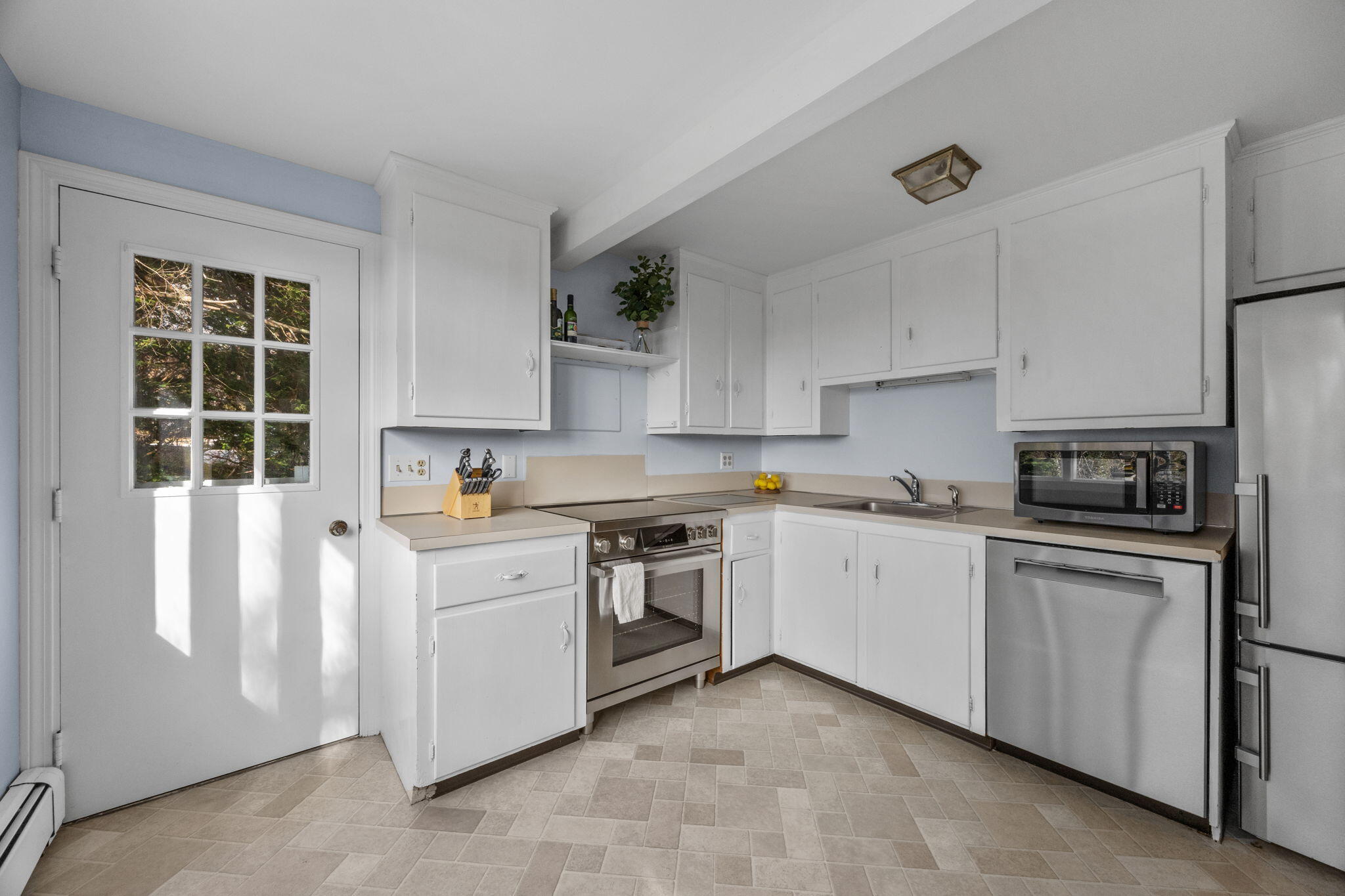 144 Barn Hill Road Chatham, MA 02633 - Photo 10 of 24 a kitchen with white cabinets stainless steel appliances and a window