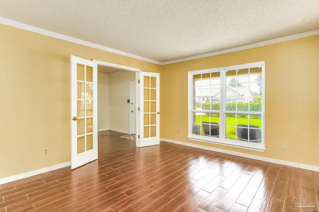 a view of empty room with wooden floor and fan