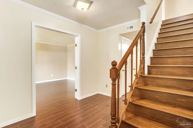 an empty room with wooden floor and fan