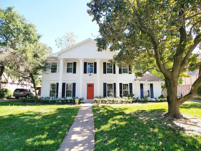 a front view of a house with a garden and trees