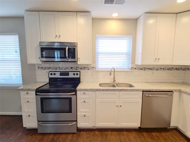 a kitchen with white cabinets stainless steel appliances and sink