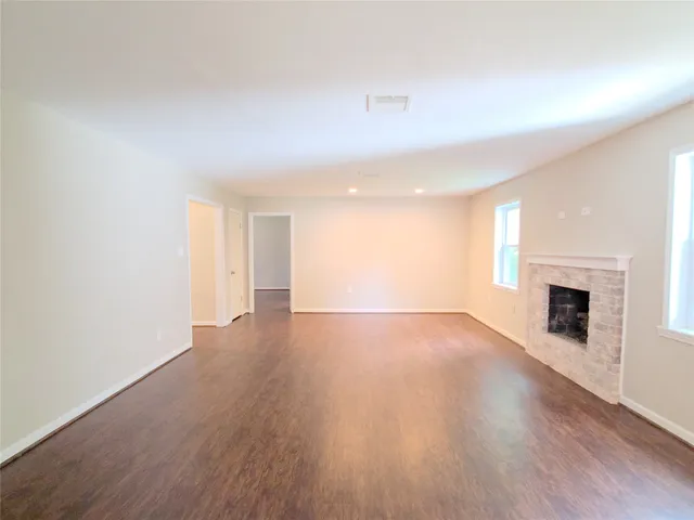 a view of an empty room with wooden floor and a fireplace