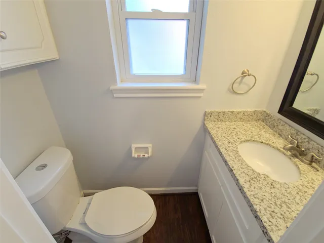 a bathroom with a granite countertop toilet sink and mirror
