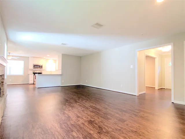 a view of an empty room with window and wooden floor