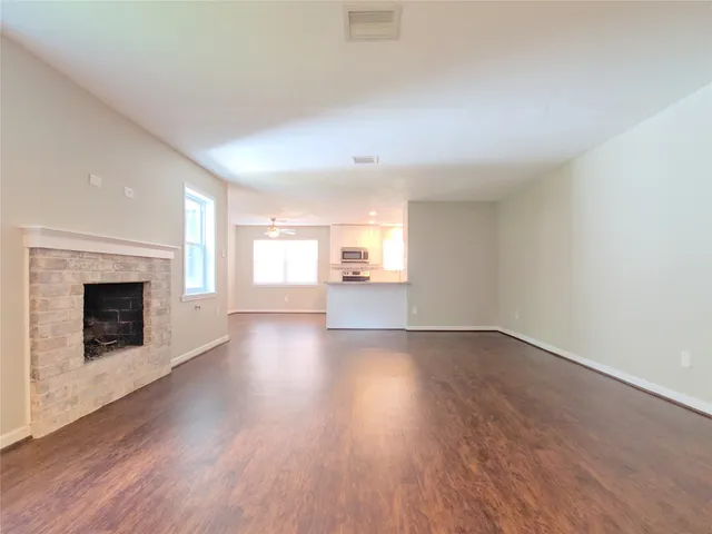 an empty room with wooden floor fireplace and windows